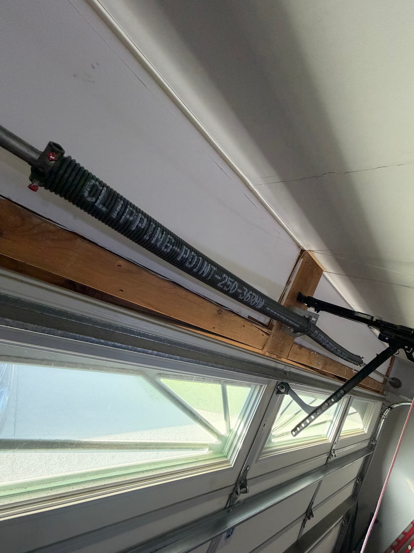 Close-up of a torsion spring and opener rail above a garage door