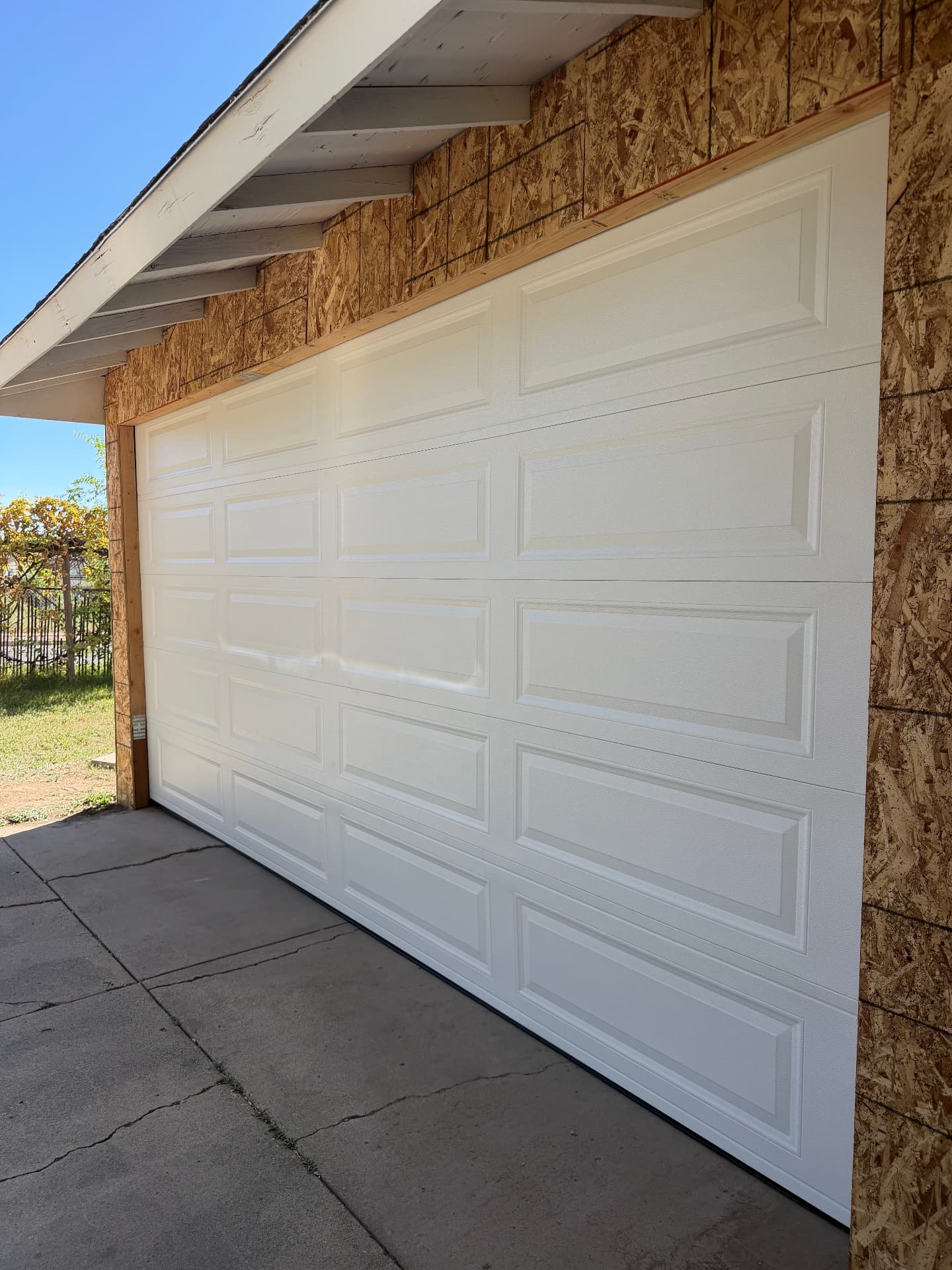 White raised-panel garage door installed on a home under construction