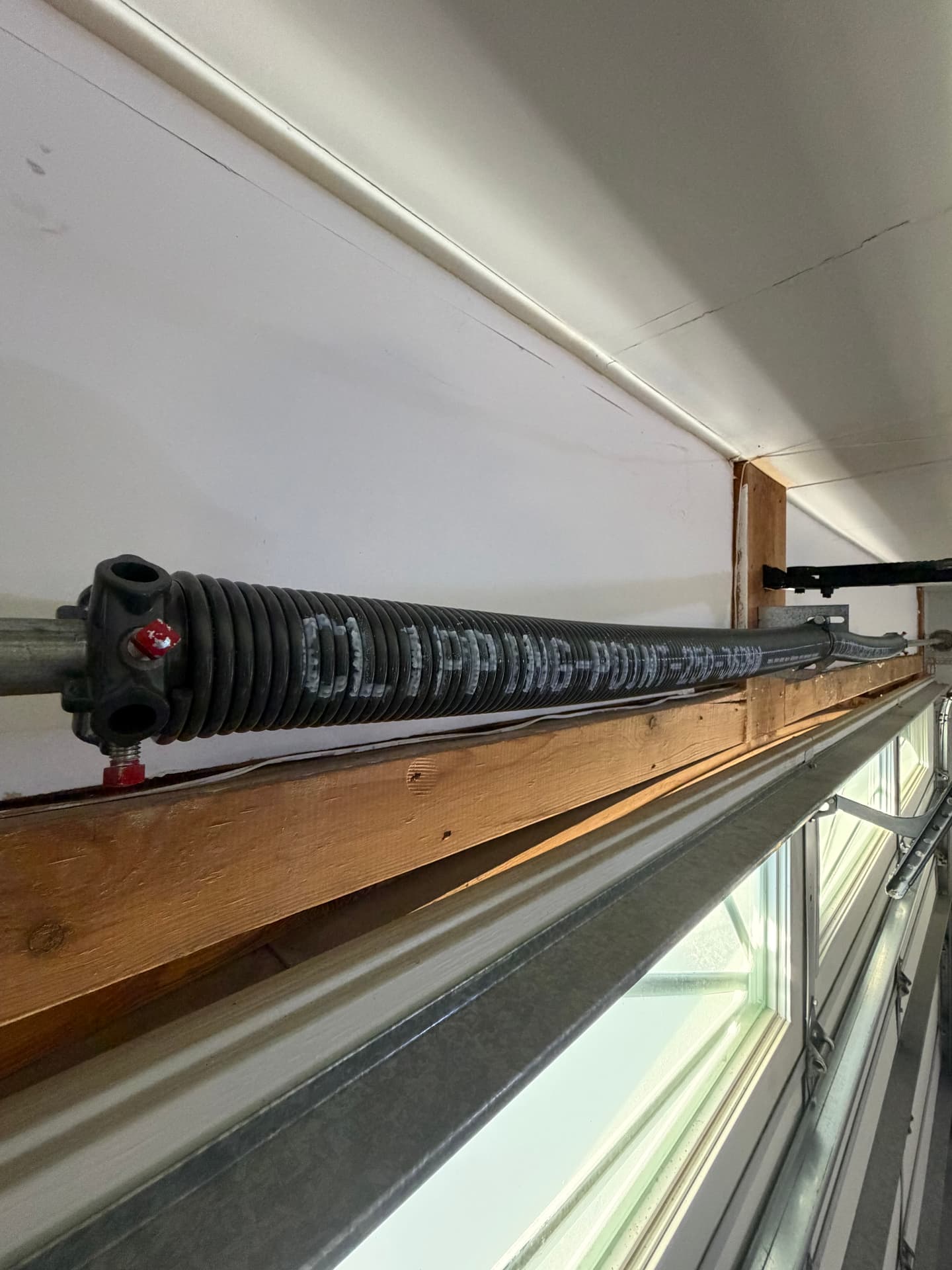 Torsion spring mounted above a garage door track